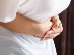Osoba trzyma się za brzuch, odczuwając ból po lewej stronie brzucha.